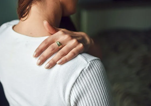 Vrouw in witte trui heeft pijn tussen schouderbladen stress gerelateerd.